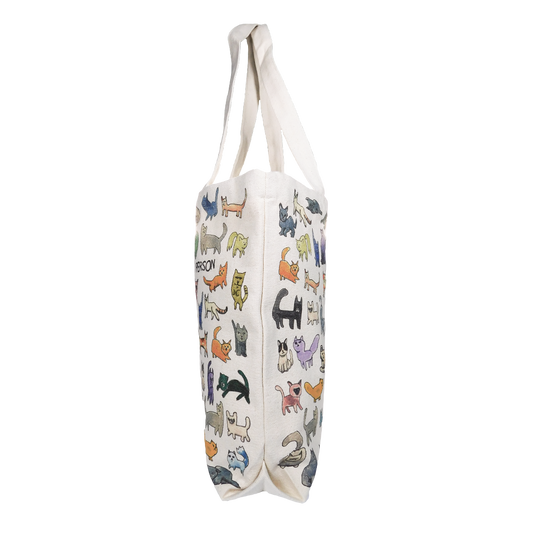 A medium-sized tote bag featuring a variety of colorful cat illustrations, with the text 'AT PETCO' on the bottom. The bag is primarily beige in color and has two white handles.