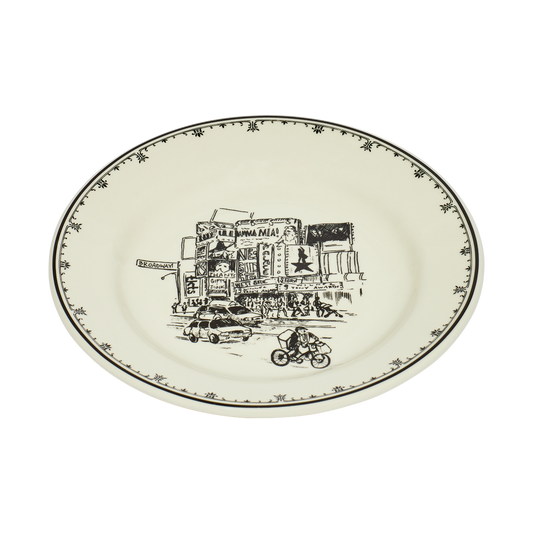 Round ceramic plate with black line art design of a city street scene on a white background