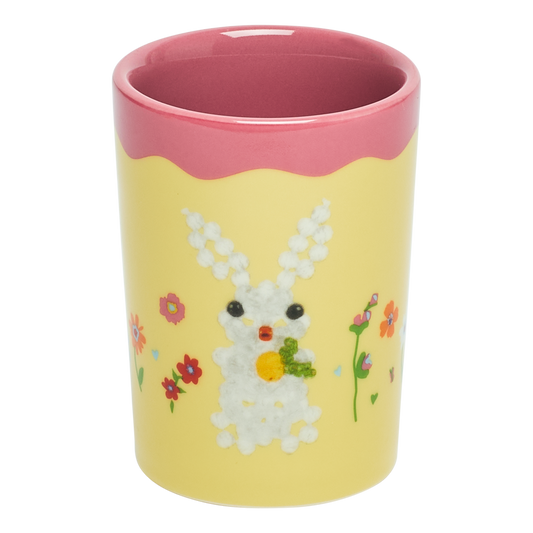Yellow cup with a rabbit design and pink rim on a white background