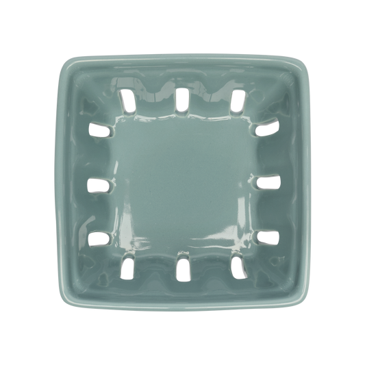 Green ceramic planter with drainage holes on a white background