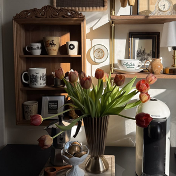 Vase of tulips on a table with shelves in the background