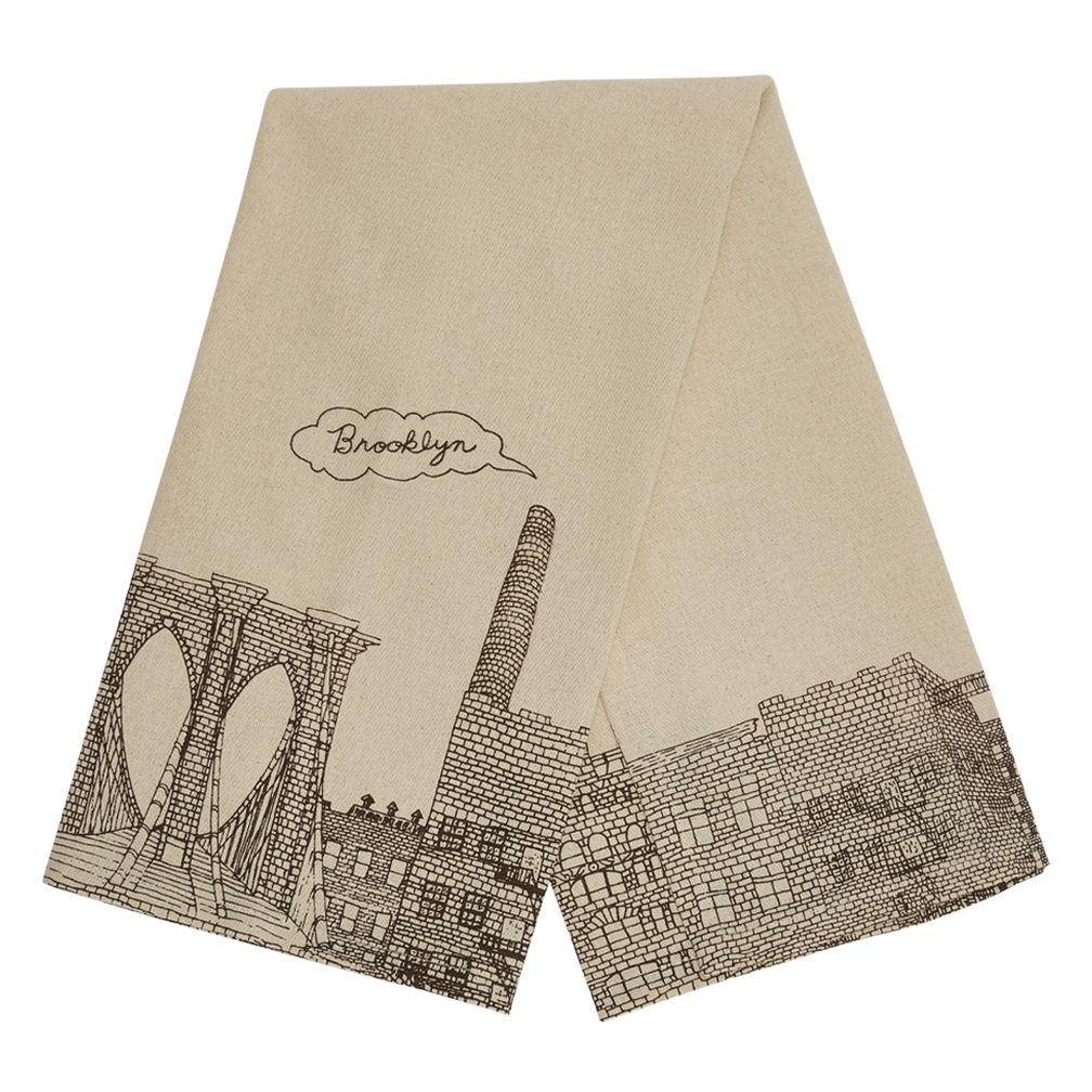 Folded Brooklyn tea towel with hand drawn bridge and neighborhood artwork, ideal for drying dishes, lining baskets, or gifting to Brooklyn lovers