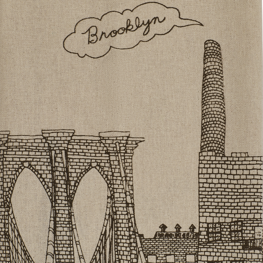 Close up of the Brooklyn tea towel design showing detailed brown linework, Brooklyn lettering, bridge arches, and city architecture on textured cotton
