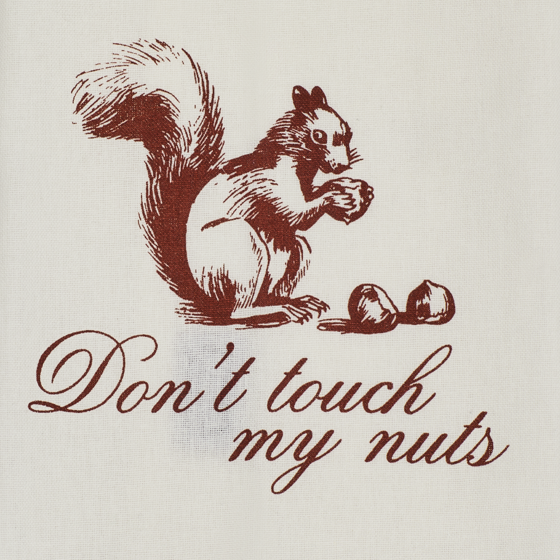 Close up of the Don’t Touch My Nuts tea towel showing detailed squirrel artwork, acorns, and cheeky red script on white cotton