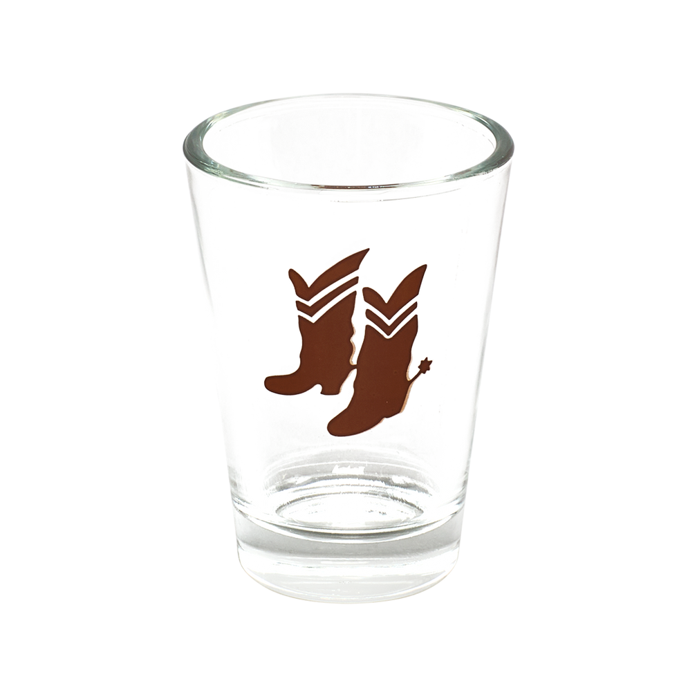 Clear glass shot glass with brown cowboy boot design on a white background