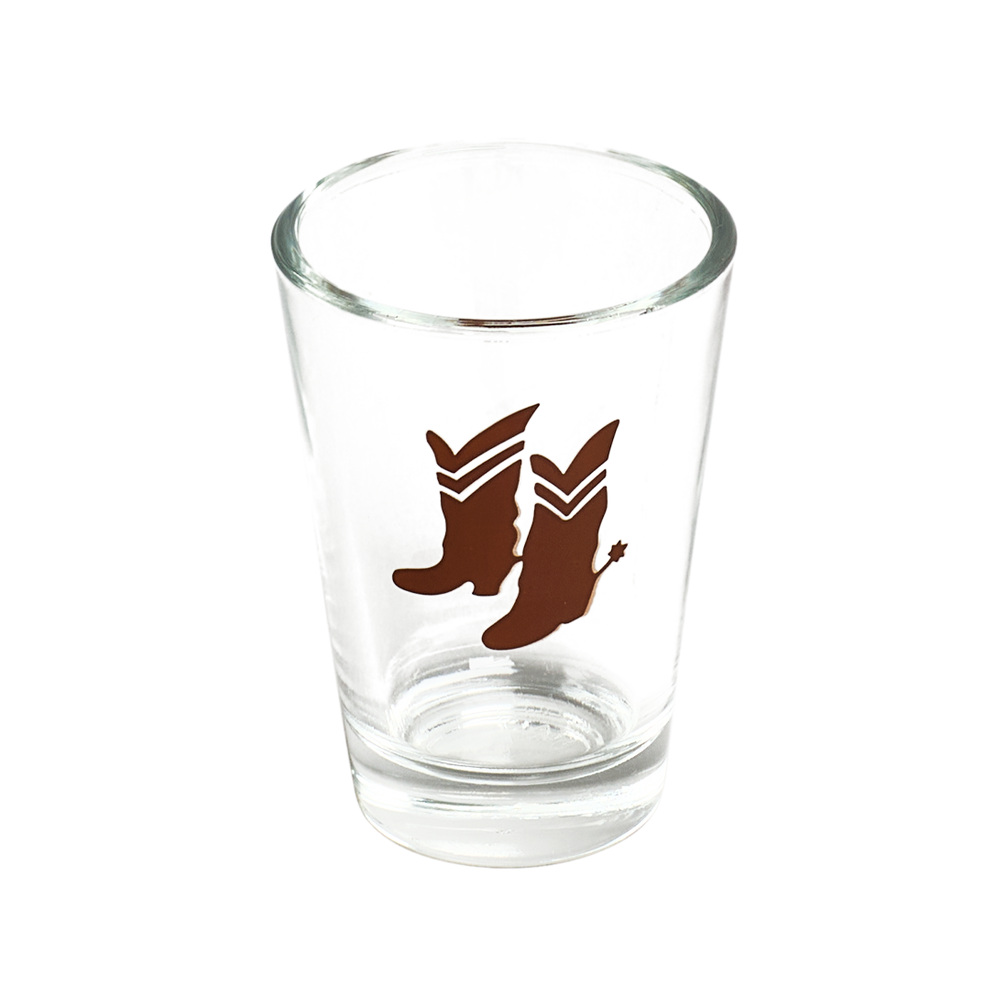Clear glass shot glass with brown boot design on a white background