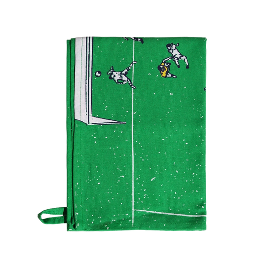 Green Soccer Field tea towel featuring a soccer pitch and tiny illustrated players, shown folded with hanging loop visible.