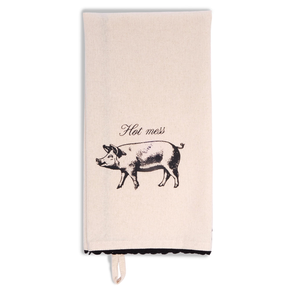 Cream tea towel folded lengthwise and hanging vertically, showing a black vintage-style pig illustration beneath the words “Hot mess,” with black scalloped trim at the bottom.