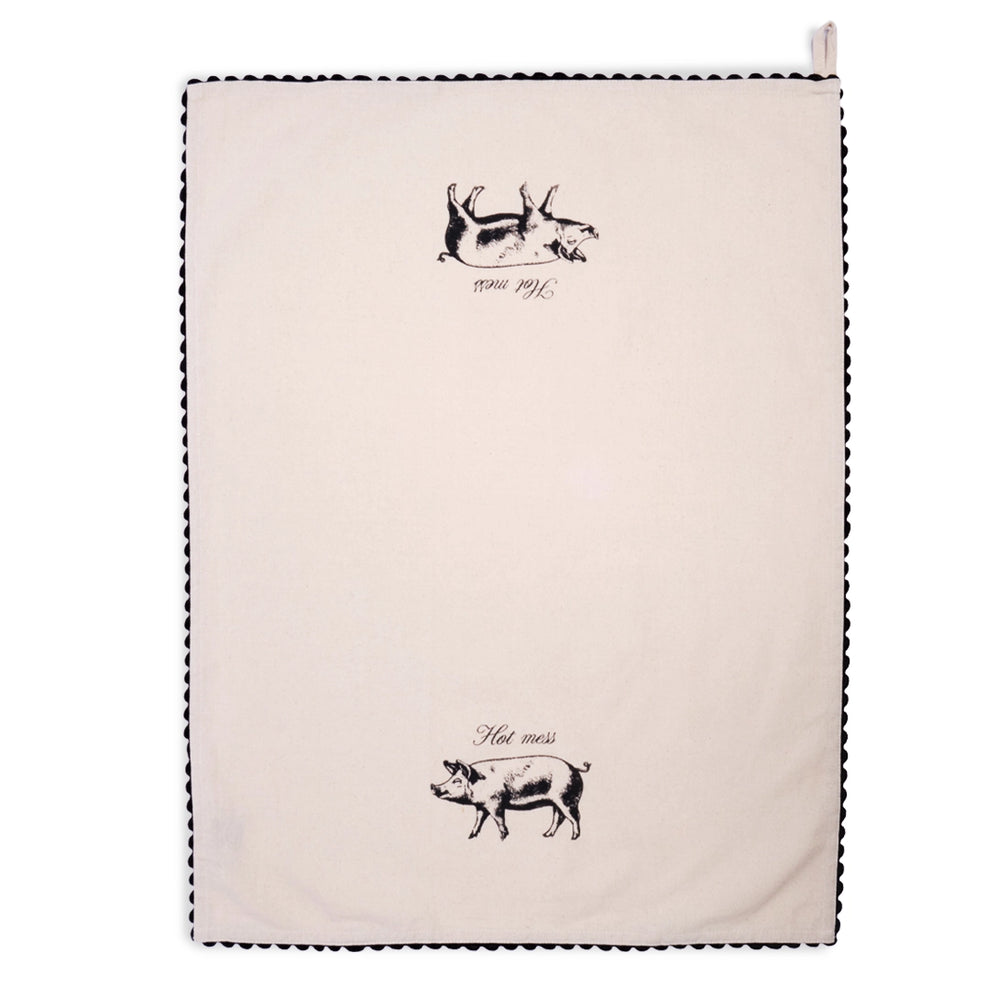 Cream Hot Mess pig tea towel draped in an inverted V shape, with a black illustrated pig and “Hot mess” lettering on the left panel and black scalloped trim along the edges.