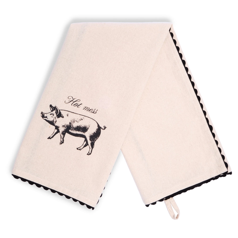 Cream Hot Mess pig tea towel laid flat vertically, showing small black pig illustrations and “Hot mess” lettering near opposite ends, with black scalloped edging around the border.