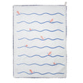 Pale blue tea towel folded lengthwise and hanging vertically, with bold blue wavy horizontal lines and a small orange fish illustration, finished with dark blue scalloped trim.