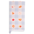 Light blue and white gingham tea towel folded lengthwise and shown vertically, featuring small red apples and golden apple pie illustrations in alternating checks, with white lace trim.