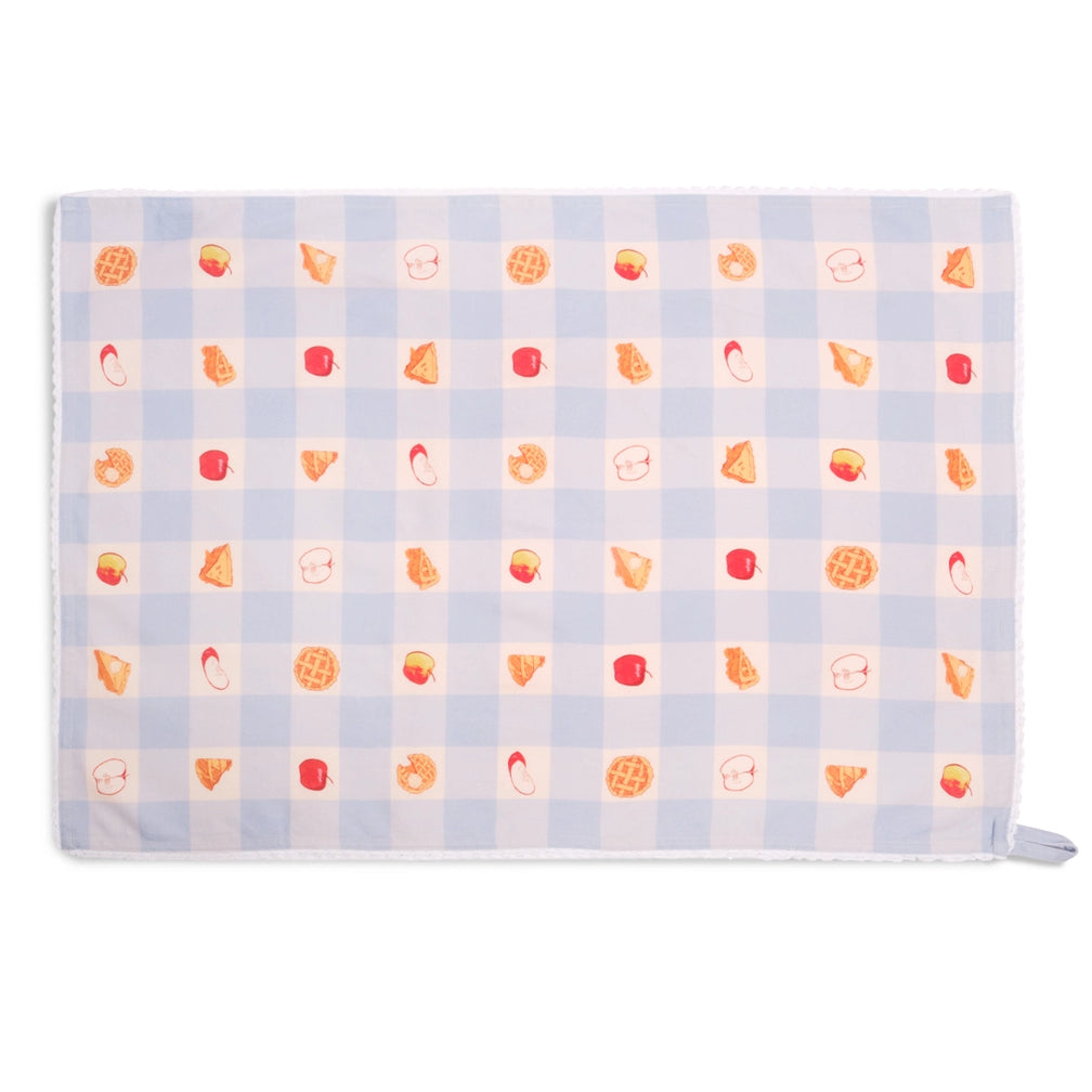 Light blue gingham apple pie tea towel spread flat horizontally, displaying a repeating pattern of red apples, apple slices, and golden lattice pies across the checked fabric.