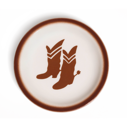 Cream glazed ceramic plate with a warm brown airbrushed rim and centered cowboy boots graphic with a spur; a playful Western accent for serving snacks, sides, or dessert.
