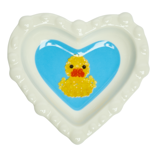 Heart-shaped dish with a yellow rubber duck on a blue background