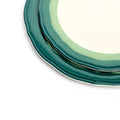 Close-up of stacked scalloped salad plates showing the two-tone teal and seagreen rim