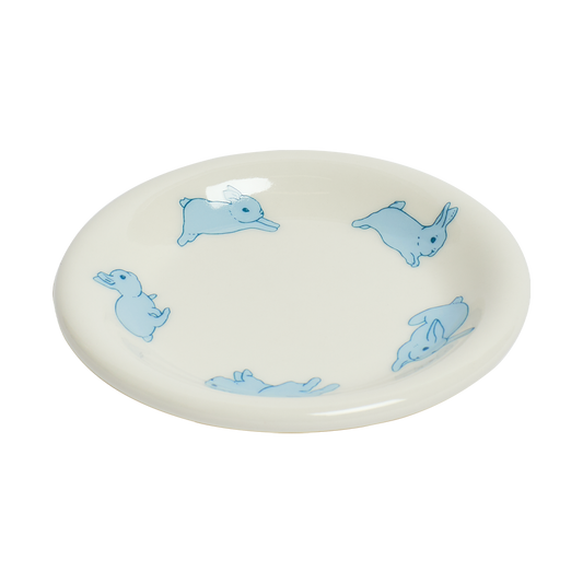 Round ceramic plate with blue rabbit illustrations on a white background