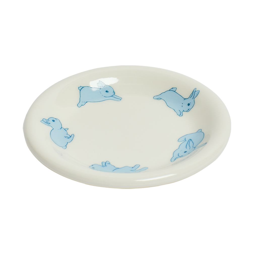 Round ceramic plate with blue rabbit illustrations on a white background