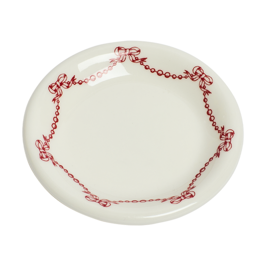 White plate with red decorative border featuring bows on a white background