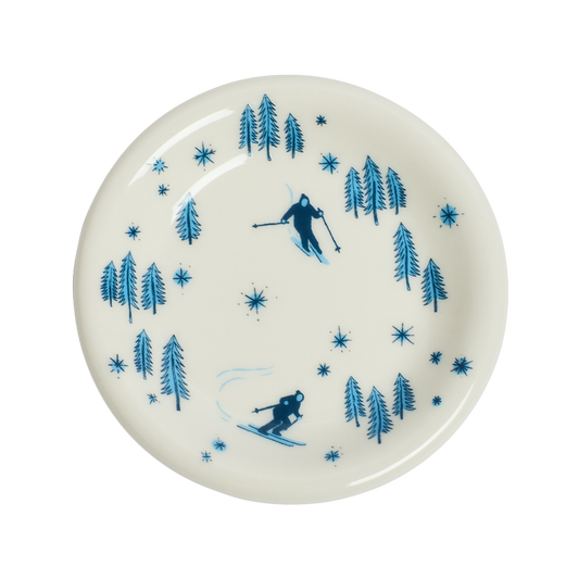 White plate with blue skiing and tree pattern on a white background