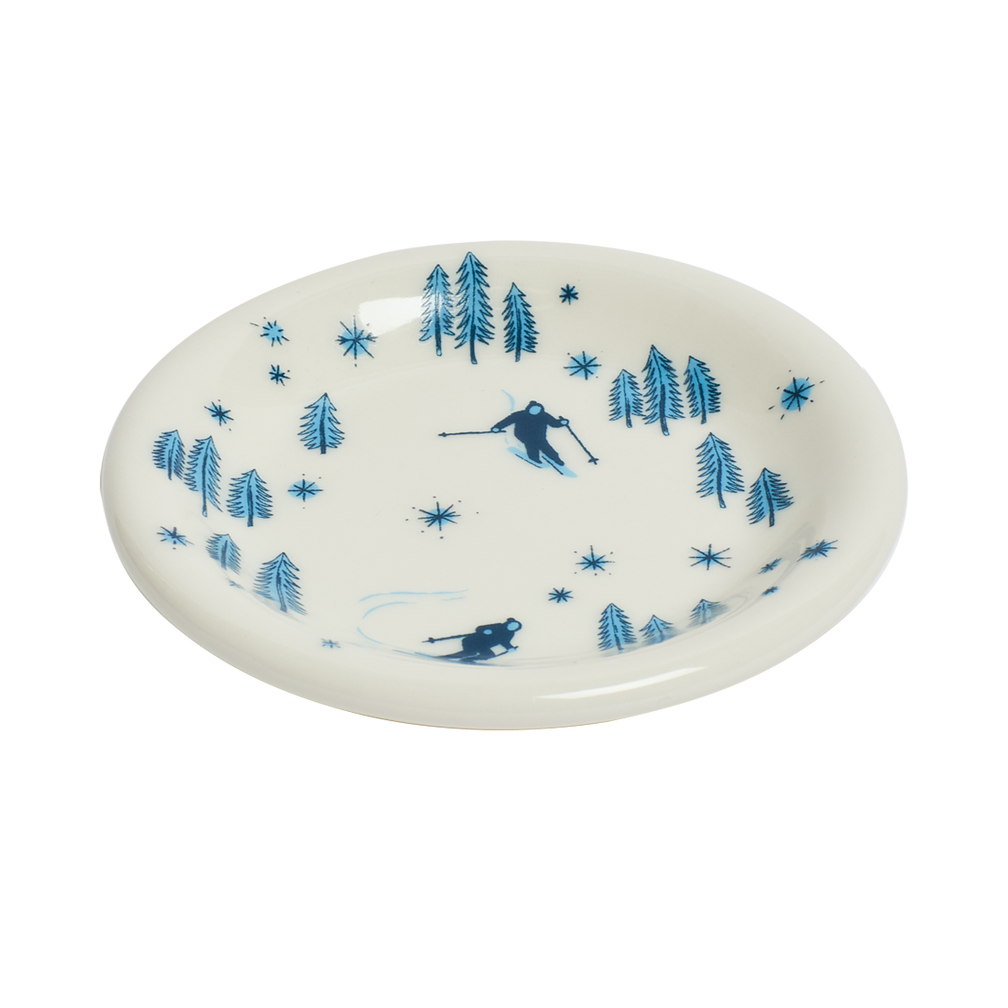 White plate with blue skiing and forest design on a white background