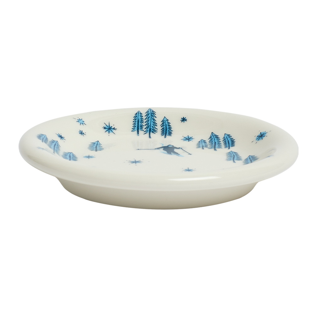 White ceramic plate with blue tree and star pattern on a white background