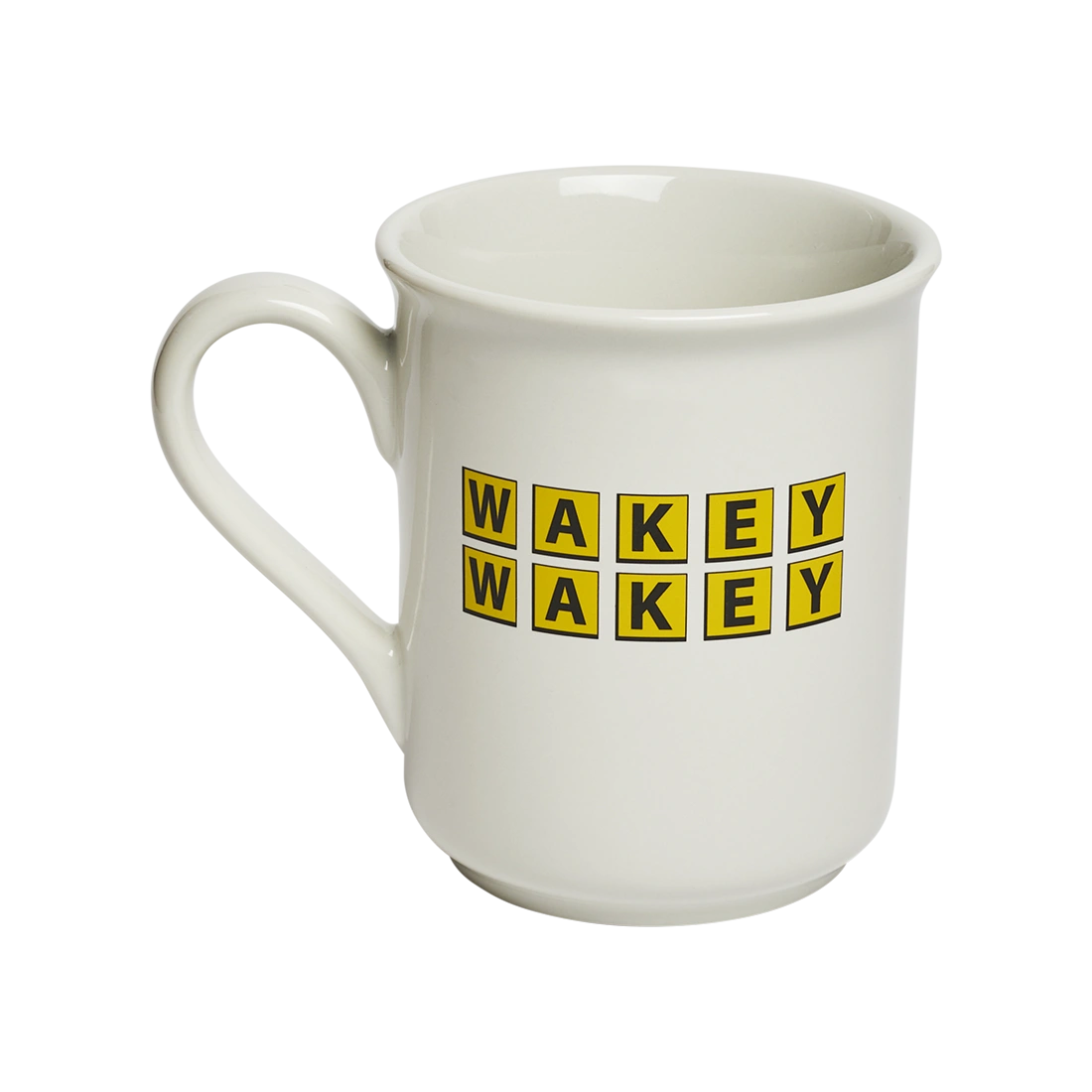 Classic white ceramic mug with “WAKEY WAKEY” printed in bright yellow tile-style lettering. Playful coffee mug perfect for morning routines, caffeine enthusiasts, and breakfast tables. Angled view.