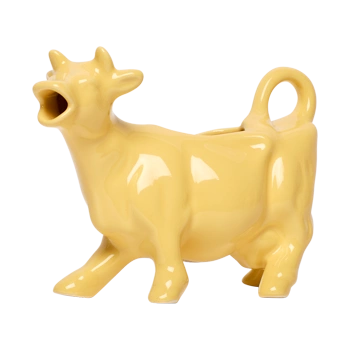 Front view of a yellow ceramic cow-shaped creamer with a playful farm-animal form, made for serving milk or cream at coffee and brunch tables.