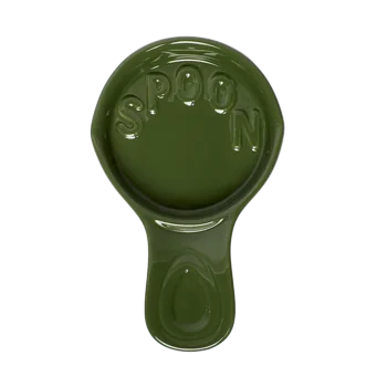 Top view of a green ceramic spoon rest with raised decorative details and a shallow basin to catch drips beside the stove.