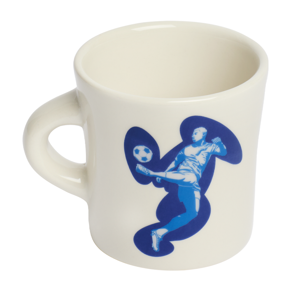 White ceramic mug with small The real football text detail in blue typography, designed for coffee lovers and soccer fans with a minimalist style