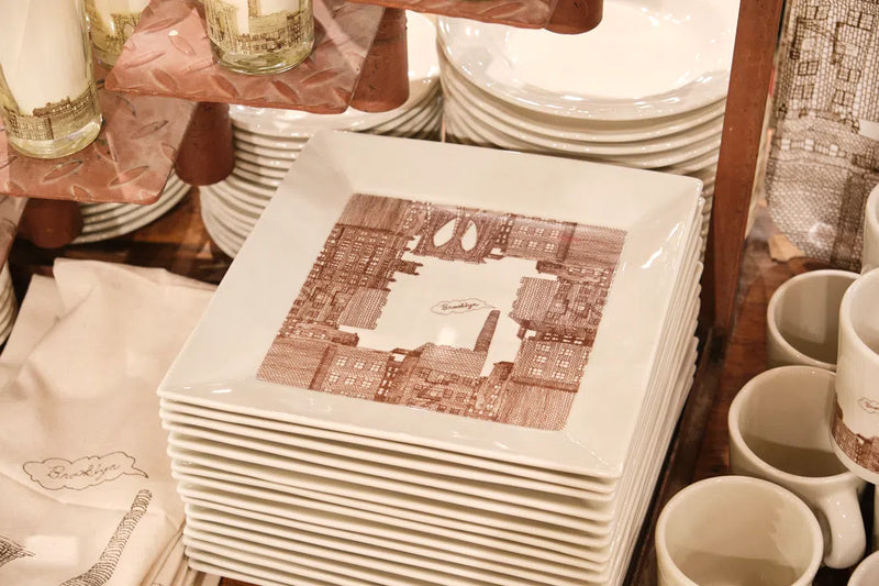 Stack of square Brooklyn trays on a store table near mugs
