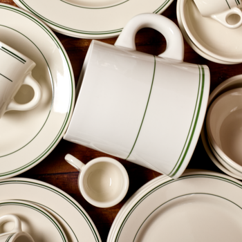 Collection of ceramic dishes with green rim on a wooden surface