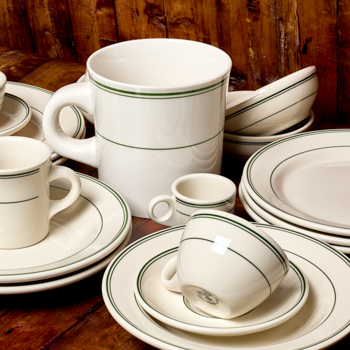 Set of ceramic dinnerware with green rim on a wooden surface