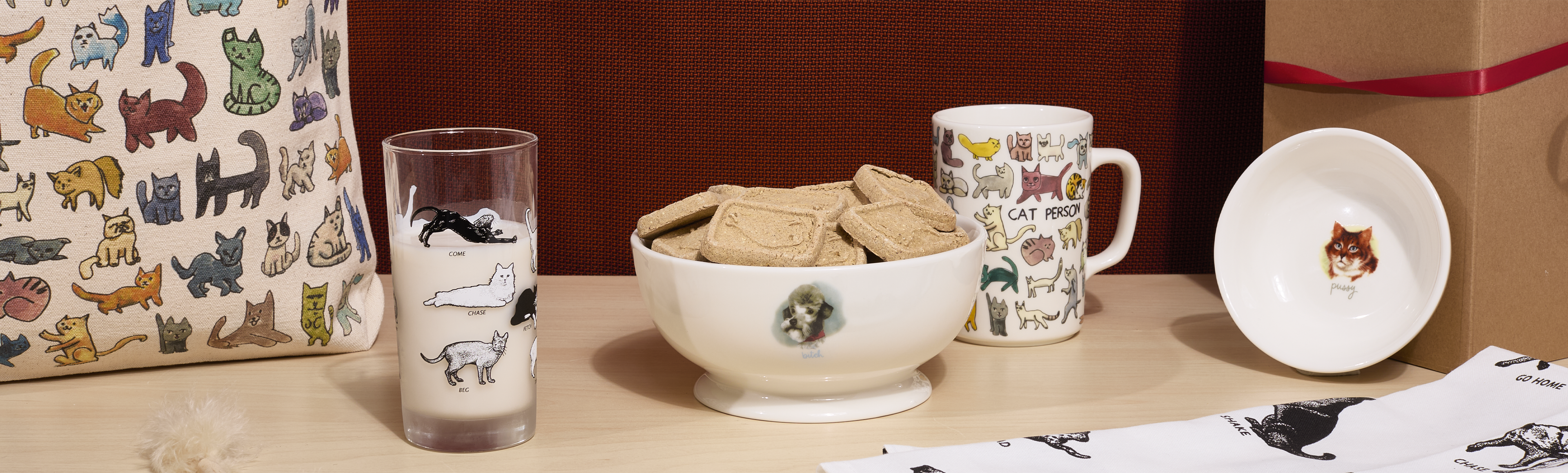 Table setting with ceramic bowl, mug, and glass featuring cat-themed designs.