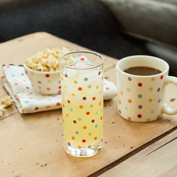 Polka dot glass with lemonade and mug with coffee on a wooden table.