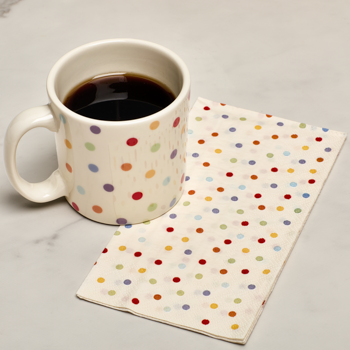 Polka dot mug with coffee on a matching polka dot napkin on a gray surface