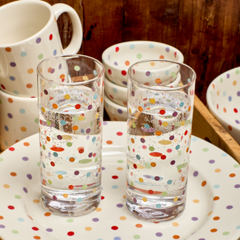 Two polka dot glasses on a matching plate with a wooden background