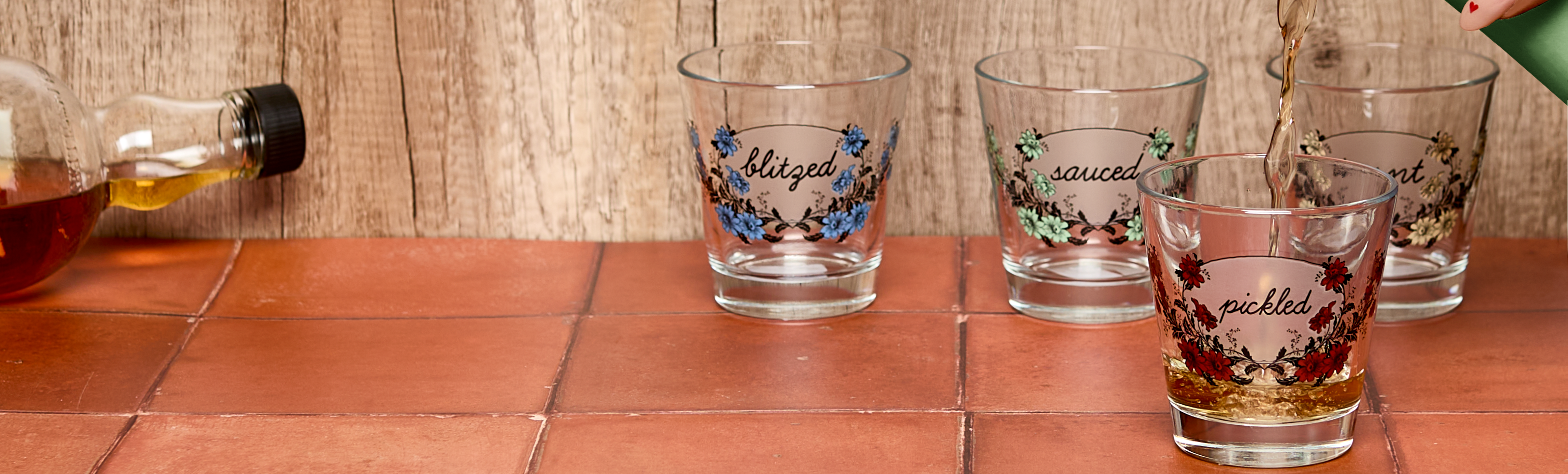 Set of four glass tumblers with floral designs on a tiled surface