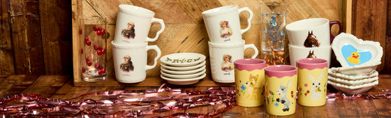 Collection of mugs and cups with animal illustrations on a wooden surface.