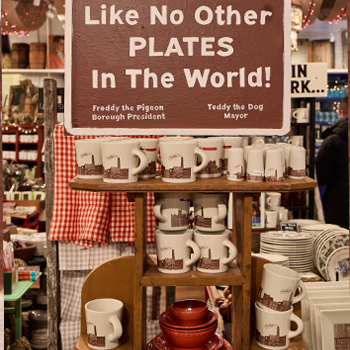 Display of mugs and plates with promotional sign in a store setting