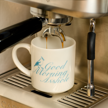 Espresso being poured into a white mug with blue text on an espresso machine.