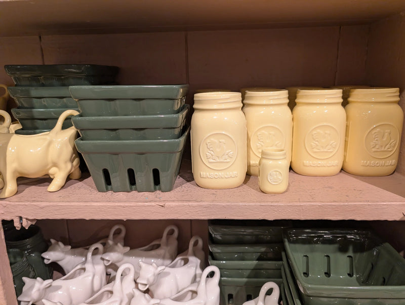 Yellow mason jars and mini jar beside green berry baskets and a yellow cow creamer