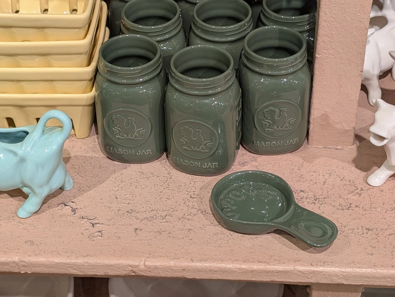 Green spoon rest beside green mason jars and a blue cow creamer
