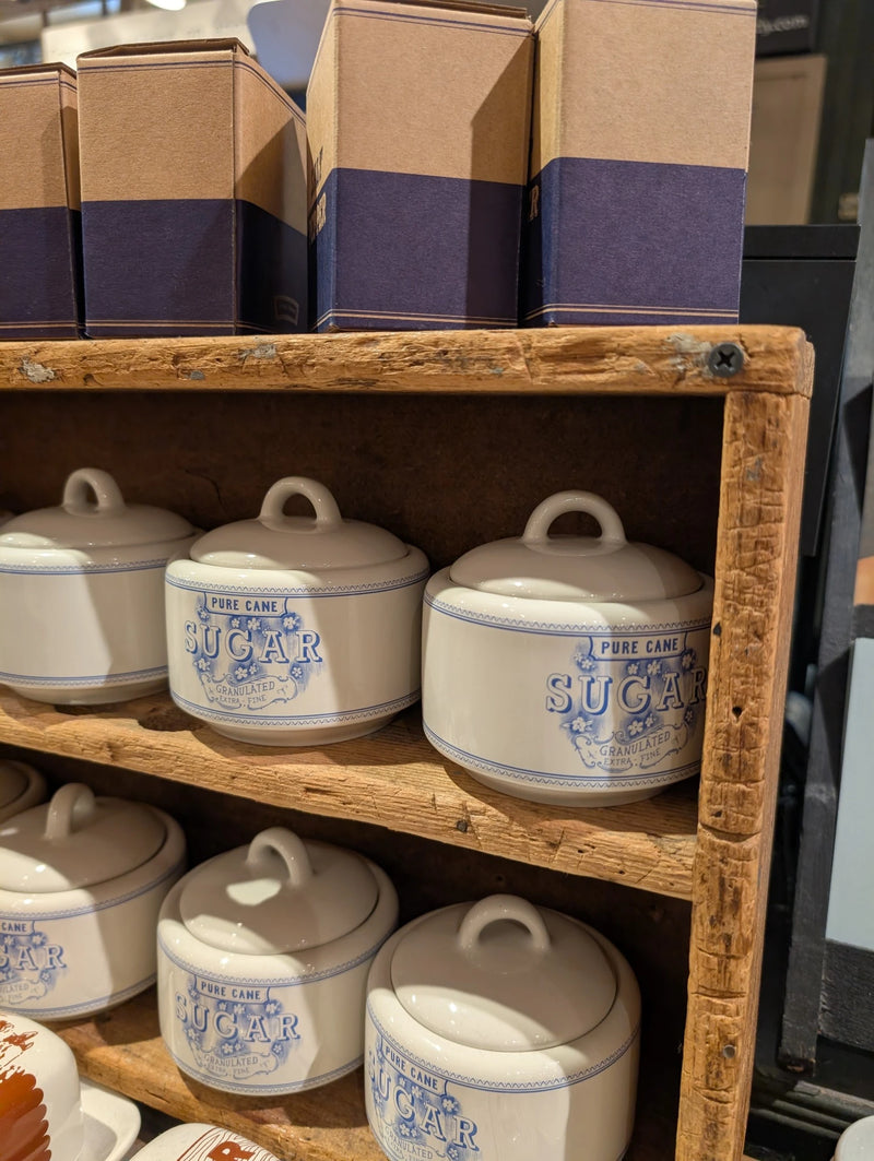Wooden crate shelves holding lidded Pure Cane Sugar bowls with boxes on top